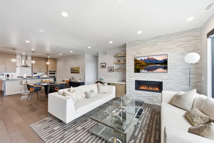 Open-concept living area featuring wood-finish flooring, recessed lighting, and a stacked stone fireplace