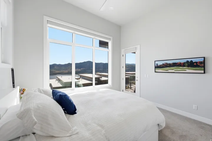Expansive window offering a mountain and water scenery, direct outdoor access, contemporary white walls, and a ceiling fan