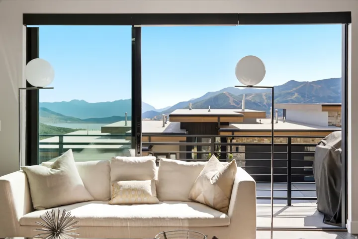 Expansive glass sliding door, metal balcony railing, and distant mountain and lake scenery
