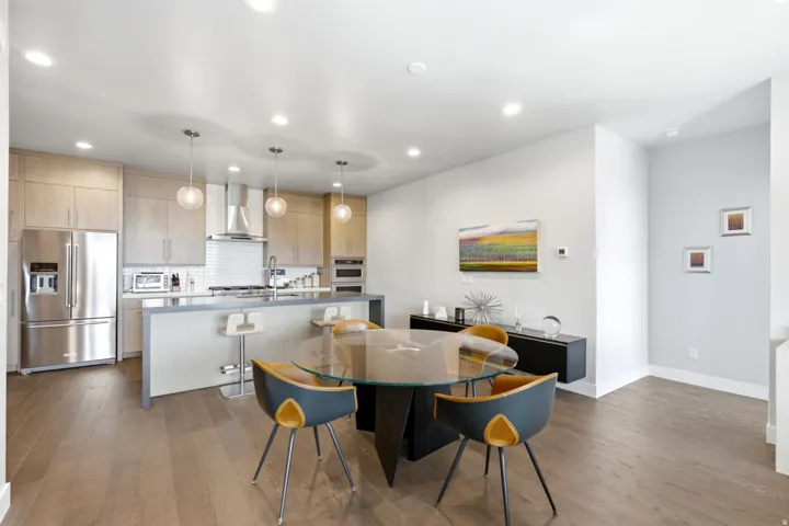 Open-concept kitchen featuring wood-finish flooring, stainless steel appliances, a center island with bar seating, and recessed lighting
