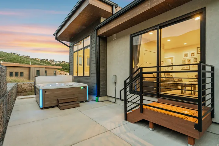 Private patio featuring a built-in hot tub with integrated lighting, concrete hardscaping, and a gabion retaining wall