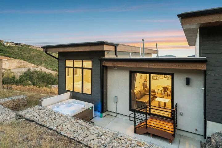 Outdoor spa, concrete patio, modern exterior siding, gabion retaining wall, sliding glass door
