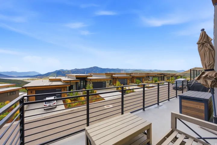 Expansive balcony with black metal horizontal railing overlooking distant mountains and water