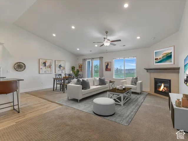 Vaulted ceiling with recessed lighting, ceiling fan, wide window, fireplace with tile surround, and wood-finish flooring