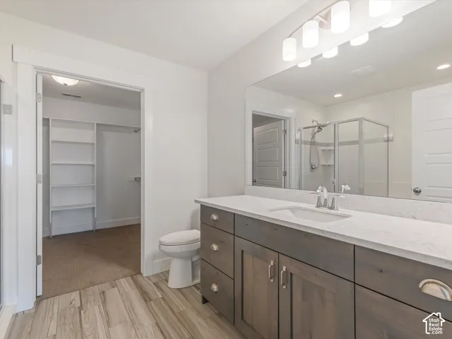 Wood-finish flooring, dark wood-finish vanity with an integrated sink, polished chrome faucet, and expansive wall-mounted mirror