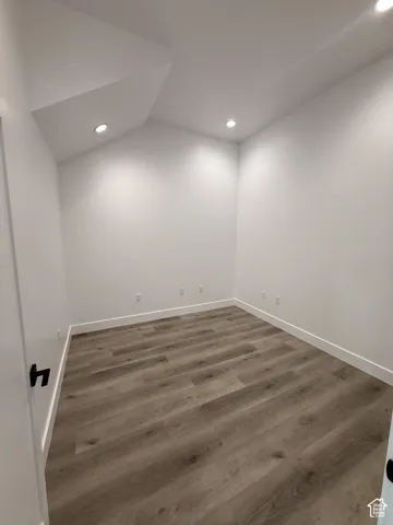 Recessed lighting, sloped ceiling detail, wood-finish flooring, and white wall finishes