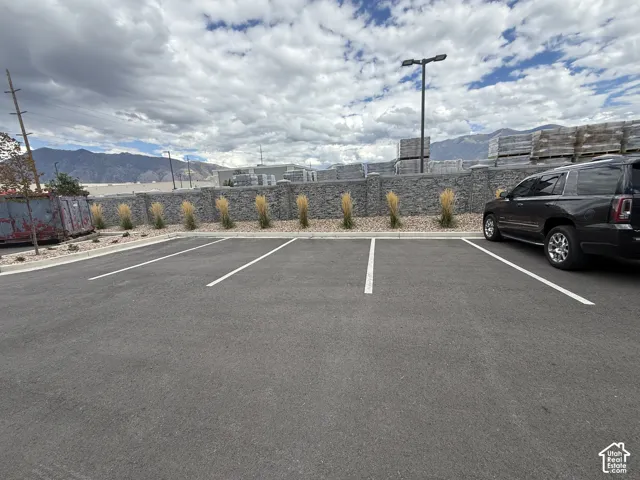 10 assigned Paved parking spots, some featuring striped spaces, rock wall, landscaped planting beds with ornamental grasses, and mountain scenery