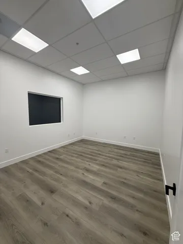 Recessed lighting with a drop ceiling, wood-finish flooring, and white walls