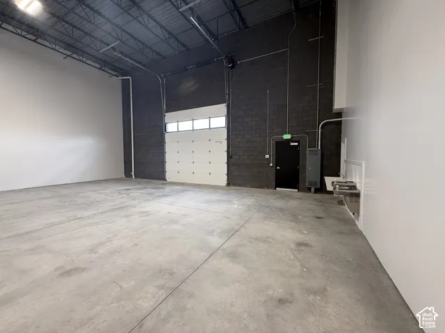 Warehouse, exposed ceiling trusses, overhead lighting, 14'x14' roll-up door, warehouse door, drinking fountains, wash tub
