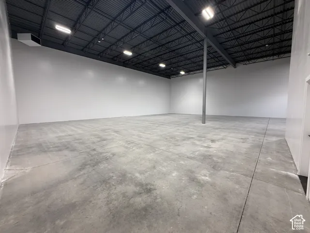 Warehouse, exposed ceiling trusses, overhead lighting, and white perimeter walls