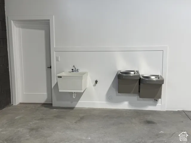 Wall-mounted utility sink, two drinking fountains, and a painted interior door