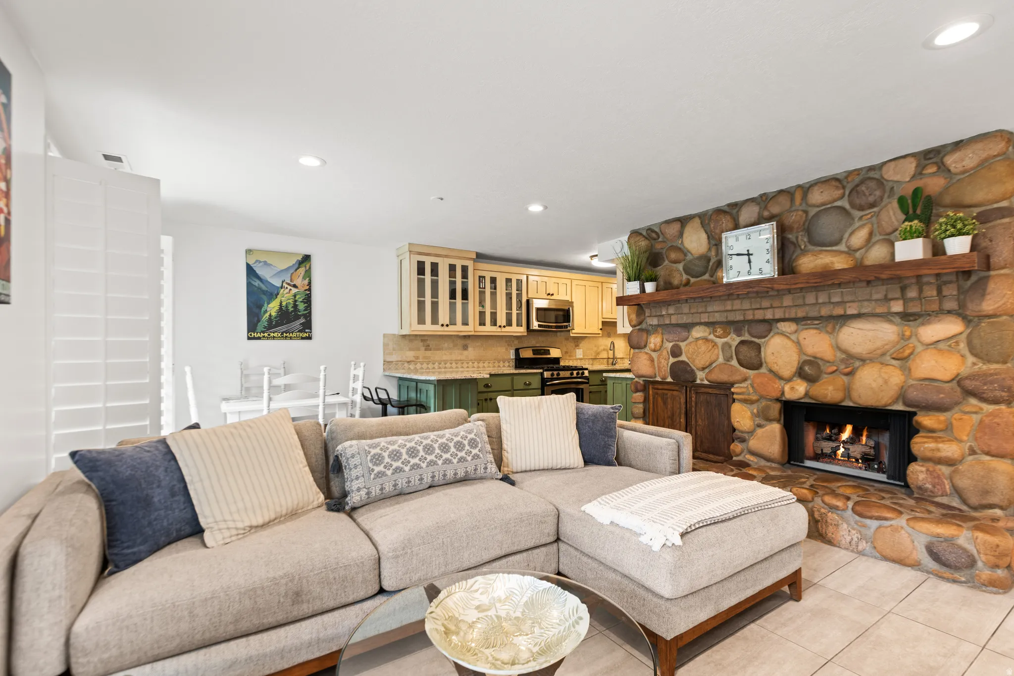 River rock fireplace with a wood mantle, tile flooring, and recessed lighting