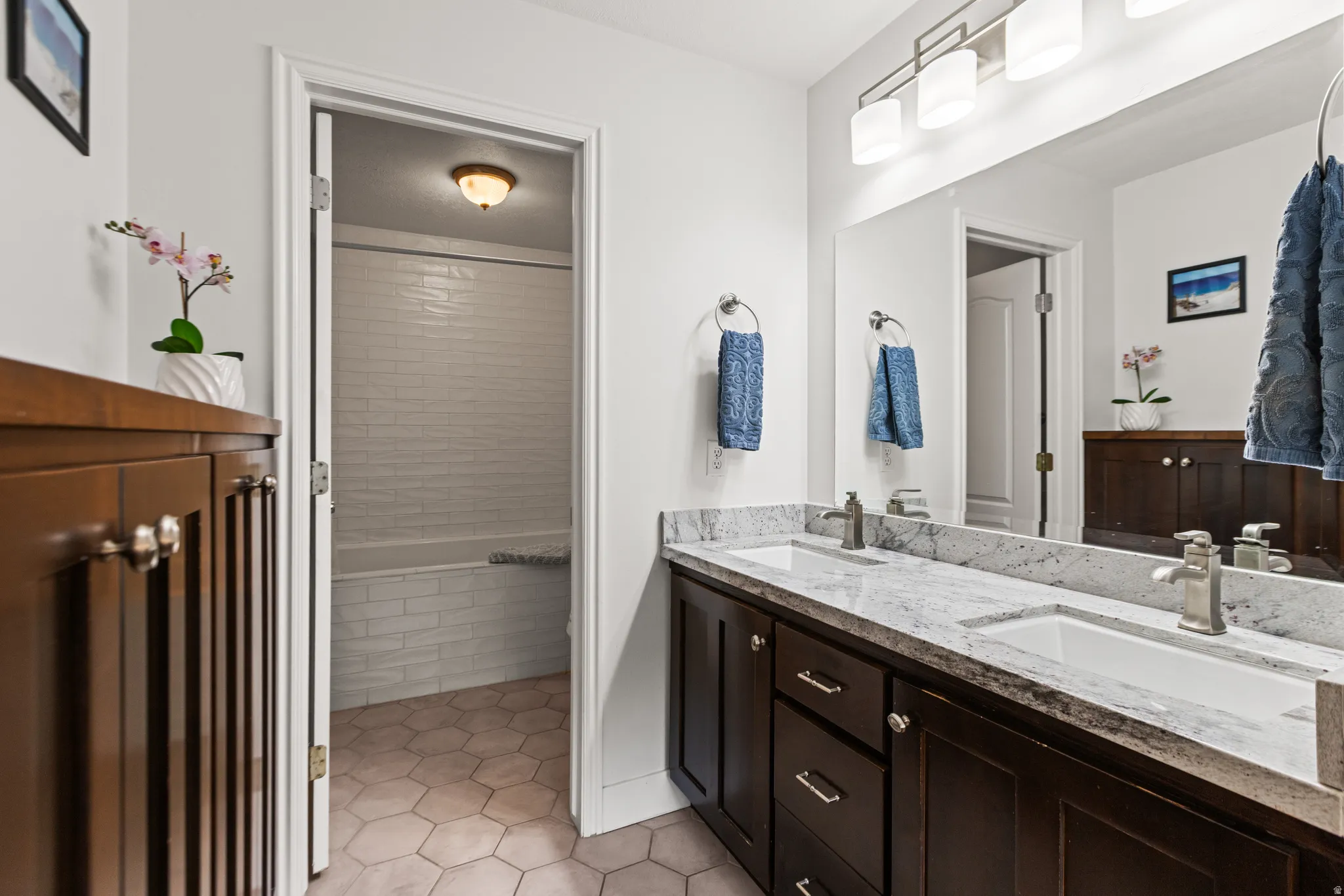 Dual vanity with undermount sinks, stone countertops, and dark wood-finish cabinetry
