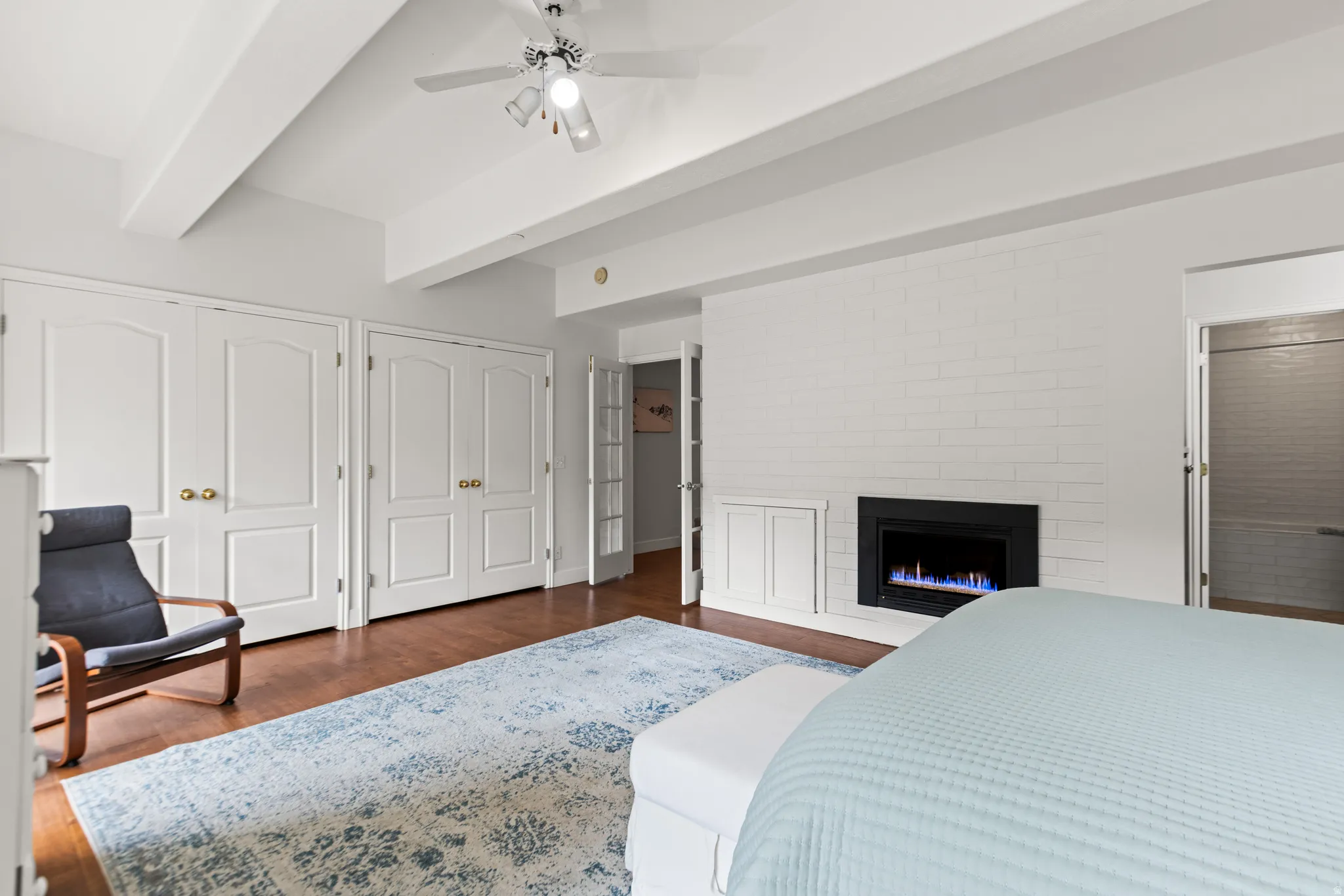 Wood-finish flooring, exposed ceiling beams, and a ceiling fan