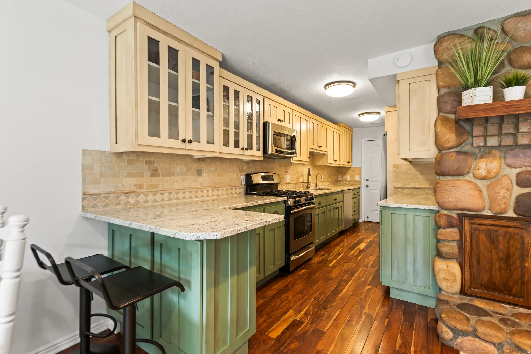 Kitchen featuring two-tone cabinetry, light-toned countertops, and wood-finish flooring