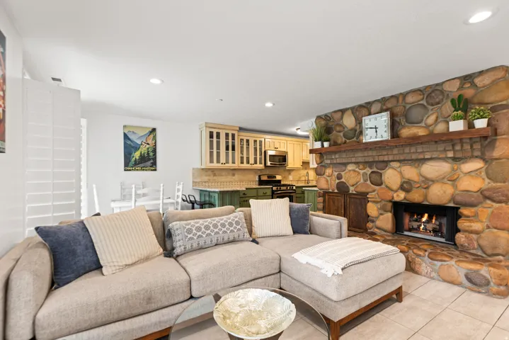 River rock fireplace with a wood mantle, tile flooring, and recessed lighting