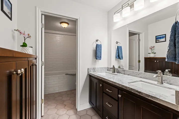 Dual vanity with undermount sinks, stone countertops, and dark wood-finish cabinetry