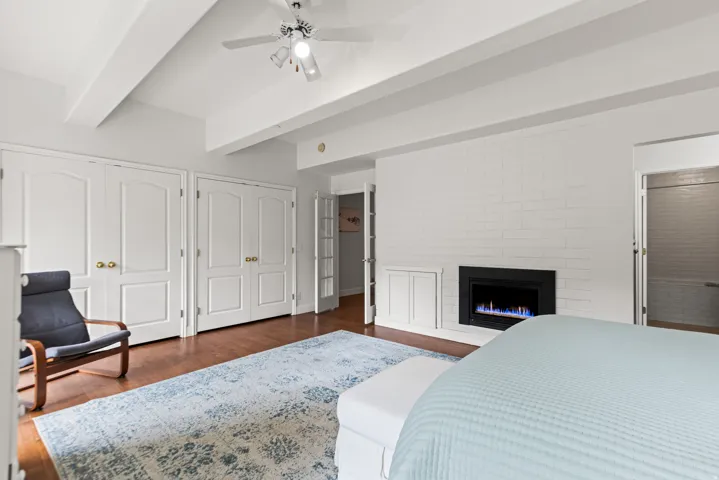 Wood-finish flooring, exposed ceiling beams, and a ceiling fan