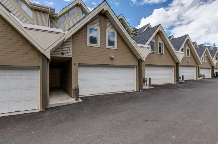 Exterior with multiple attached garages, peaked roofs, and dormer windows