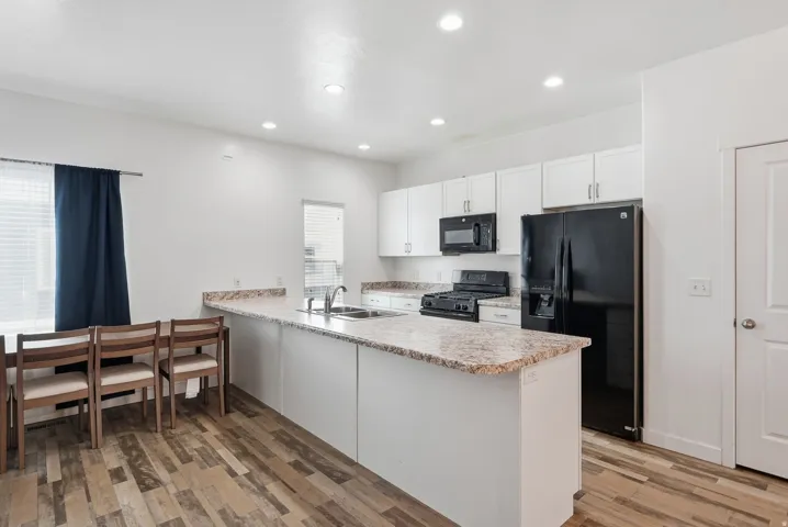 Kitchen with a breakfast bar, white cabinetry, and recessed lighting