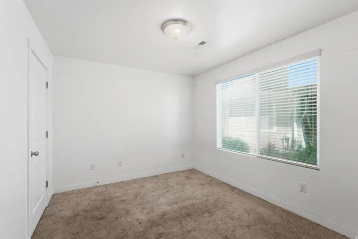 Neutral wall color, window with blinds, flush-mount ceiling light fixture, and carpet flooring