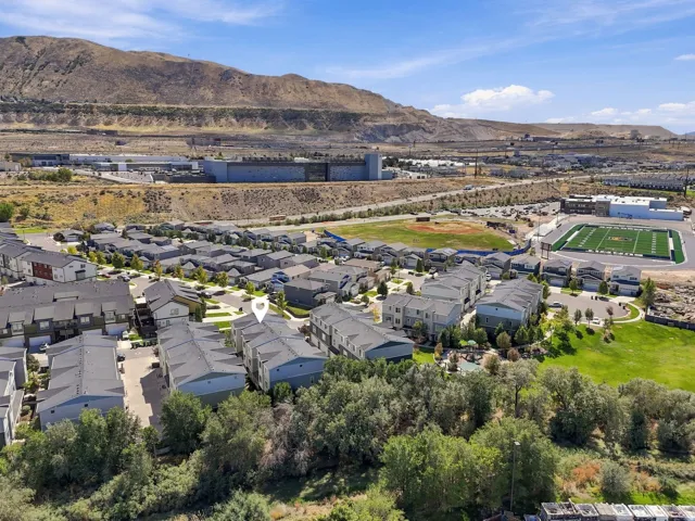 Modern townhome community with a mountainous backdrop, adjacent to a sports field and green spaces