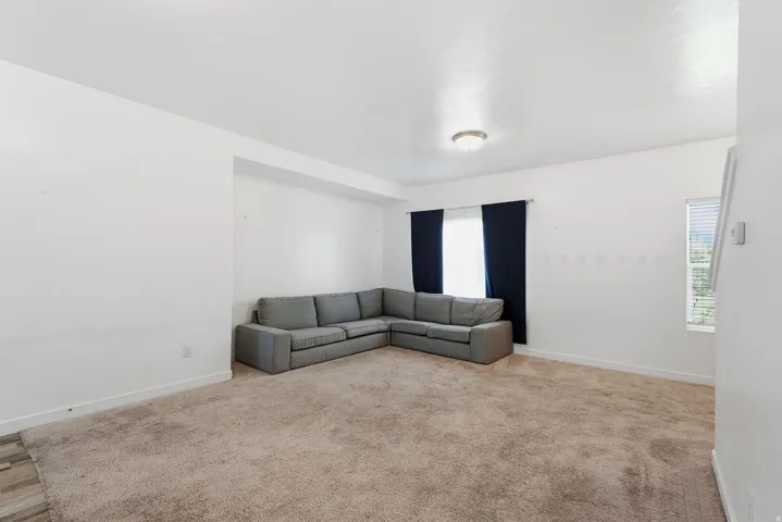 Carpeted living area featuring white walls, recessed ceiling, and a flush-mount ceiling light