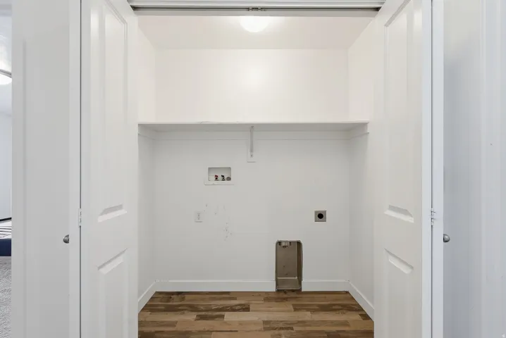 Utility closet featuring bi-fold doors, a built-in shelf, and wood-finish flooring