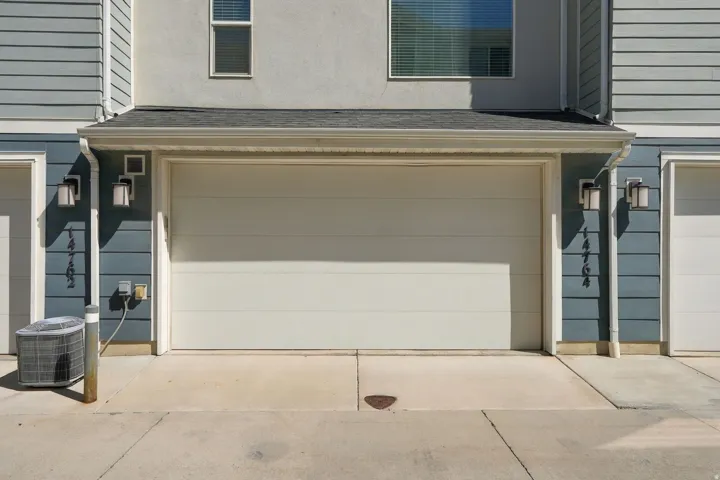 Neutral-toned garage door with exterior wall sconces, rain gutters, and siding details