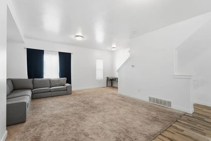 Wall-to-wall carpeting, multiple windows for natural light, white wall finishes, and wood-finish flooring