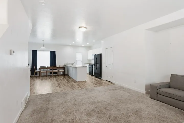 Open-concept living space featuring carpeted and wood-finish flooring, a kitchen island with a stone-finish countertop, and recessed lighting