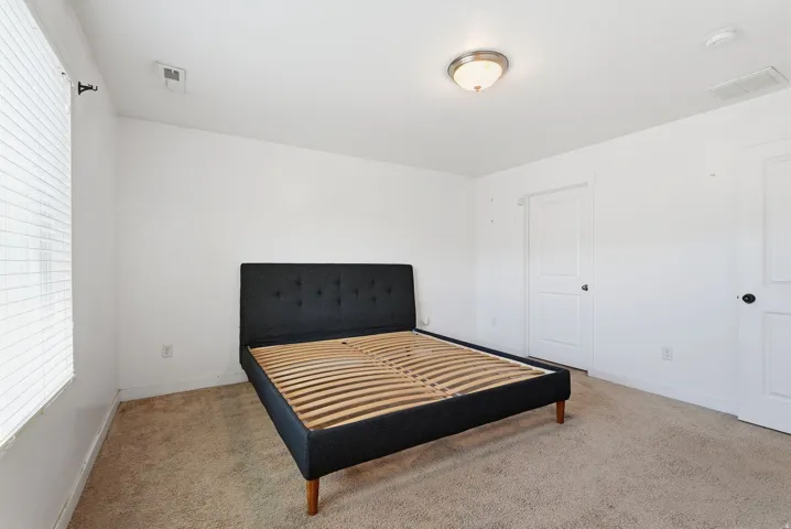 Carpeted flooring, white interior doors with black hardware, and a ceiling-mounted light fixture