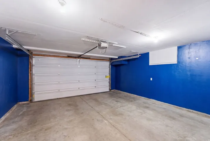 Attached garage featuring a concrete floor, white sectional door, and overhead lighting