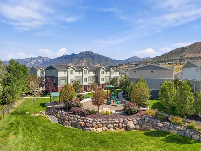 Community green space featuring a playground, shaded picnic area, and mature landscaping with a stone retaining wall