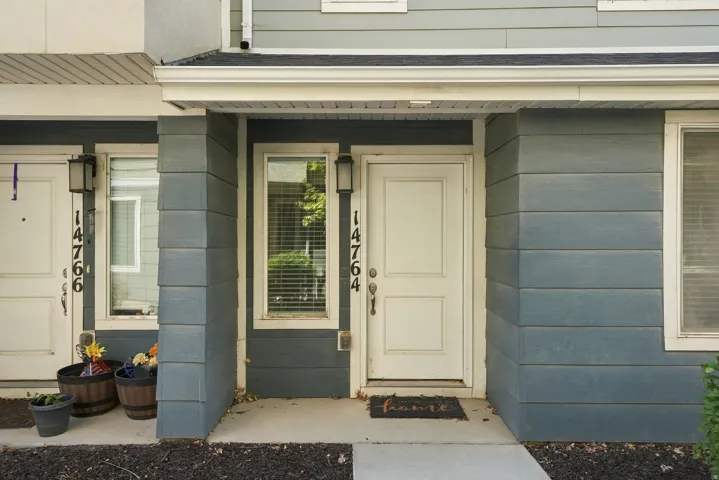 Siding exterior with contrasting trim, white entry door, and exterior lighting fixture