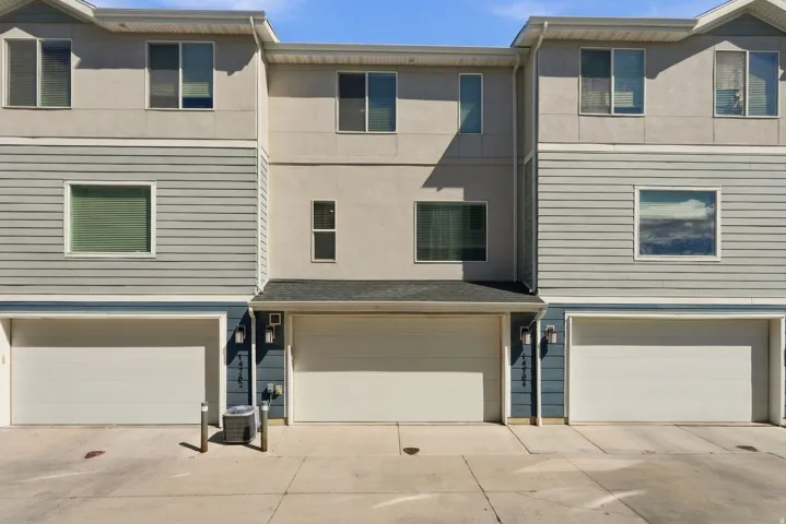 Modern townhome exterior with mixed material facade, featuring light gray horizontal siding and stucco