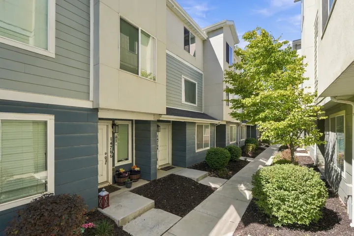Multi-level townhome exterior featuring dual-tone siding, white window trim, and a concrete walkway