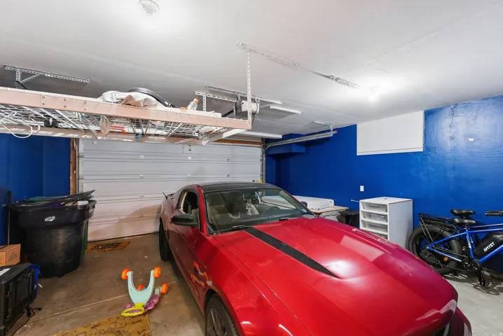 Garage featuring a white sectional door, overhead storage racks, and a wall-mounted mini-split unit