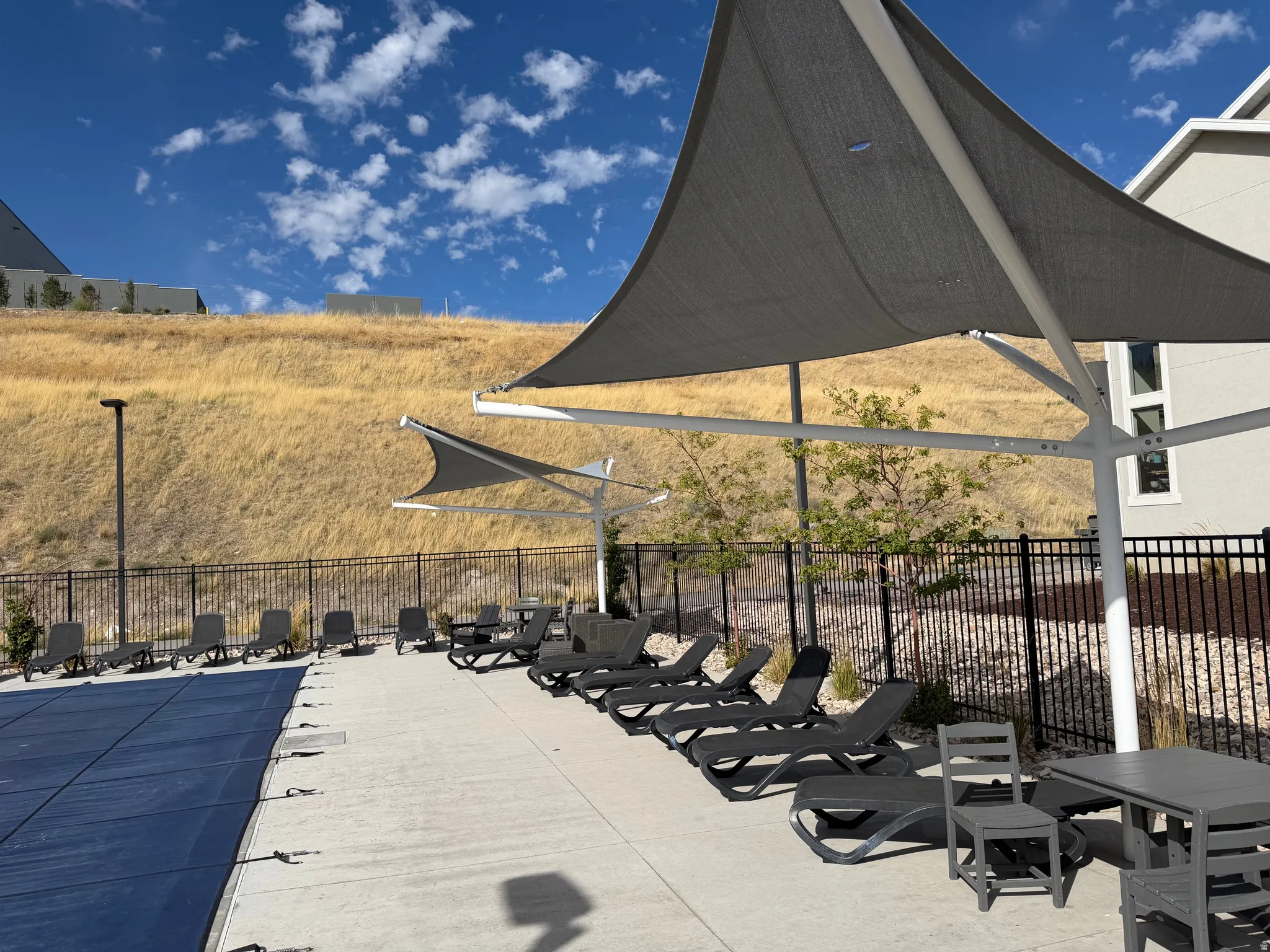 Outdoor pool area with a covered pool, multiple lounge chairs, and shade structures