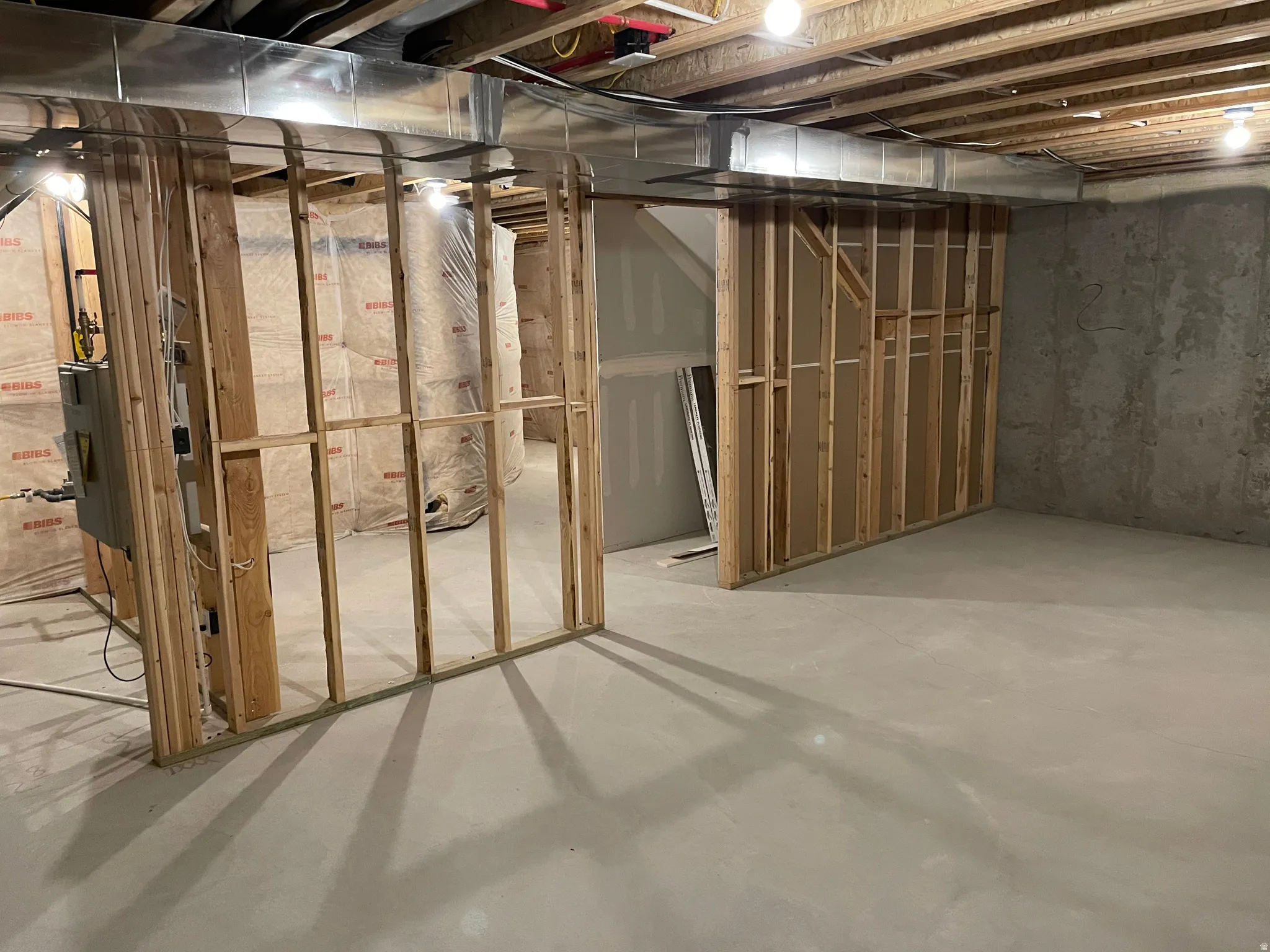 Unfinished basement with exposed ceiling joists, concrete flooring, and framed interior walls