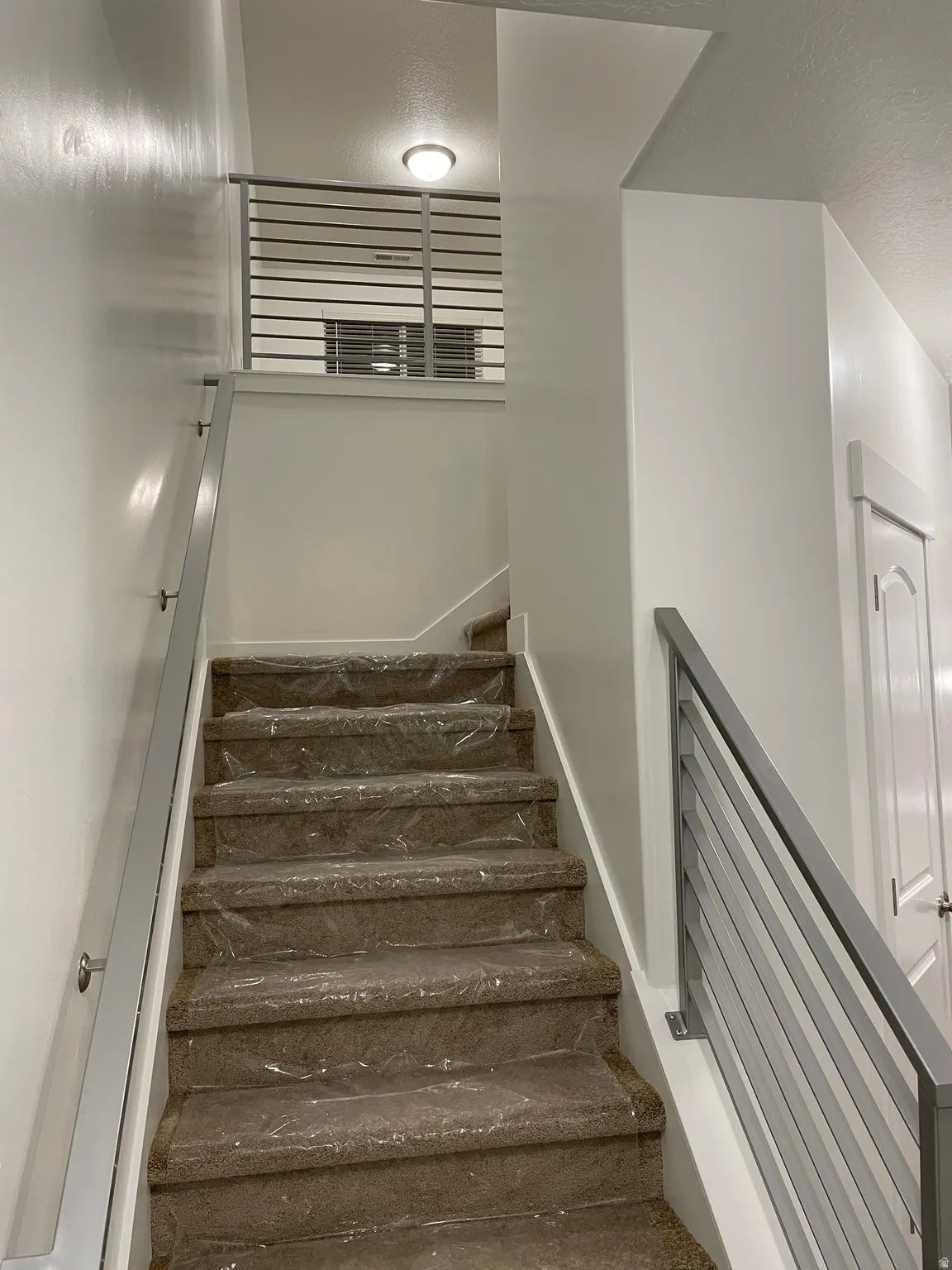 Staircase featuring carpeted treads, contemporary metal railings, and a flush-mount ceiling light