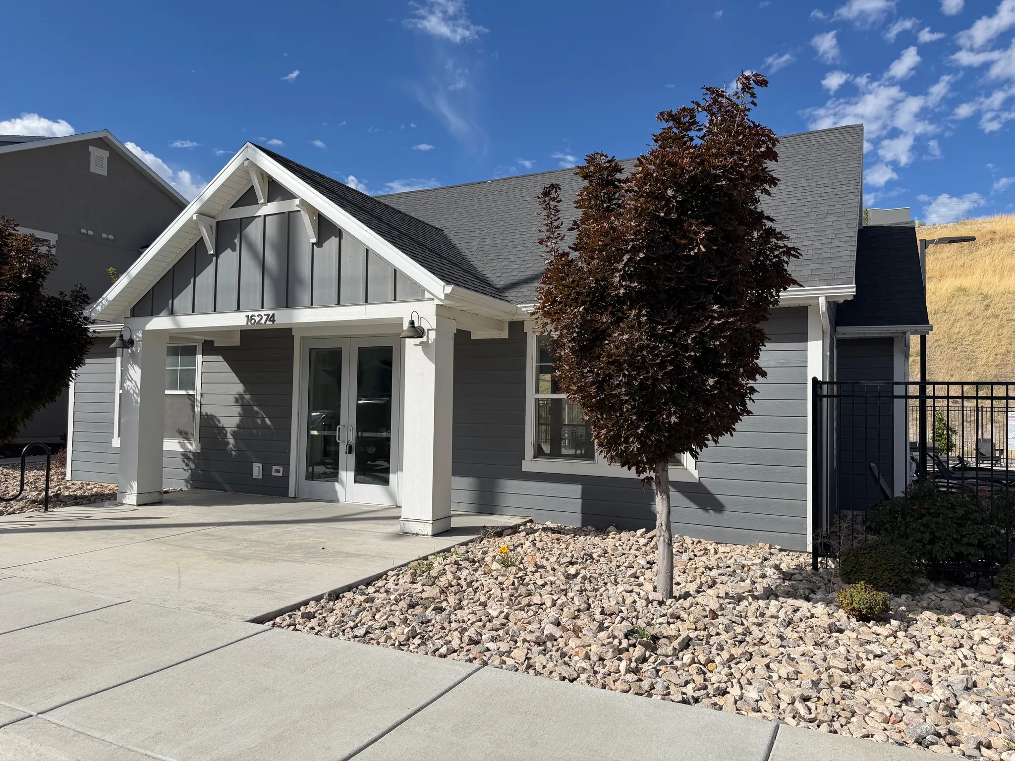 Gable roofline with white trim, horizontal siding, and double entry doors