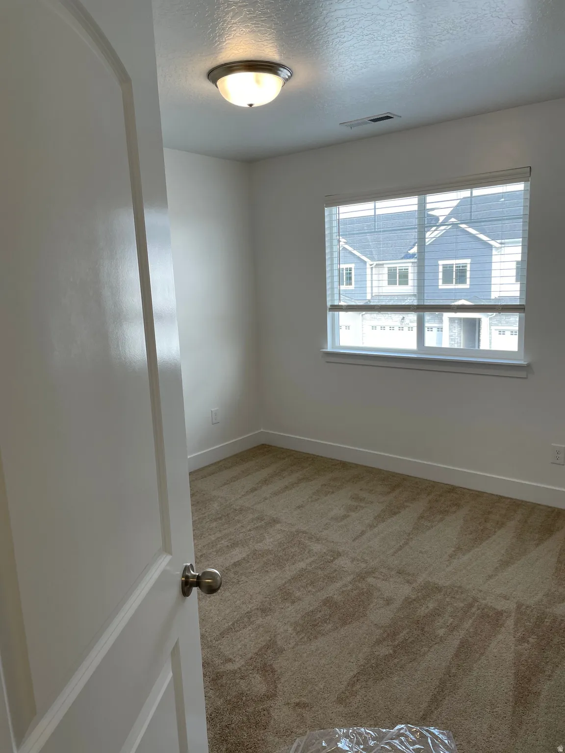 Neutral-toned carpeting, white walls, white trim, and a window with blinds