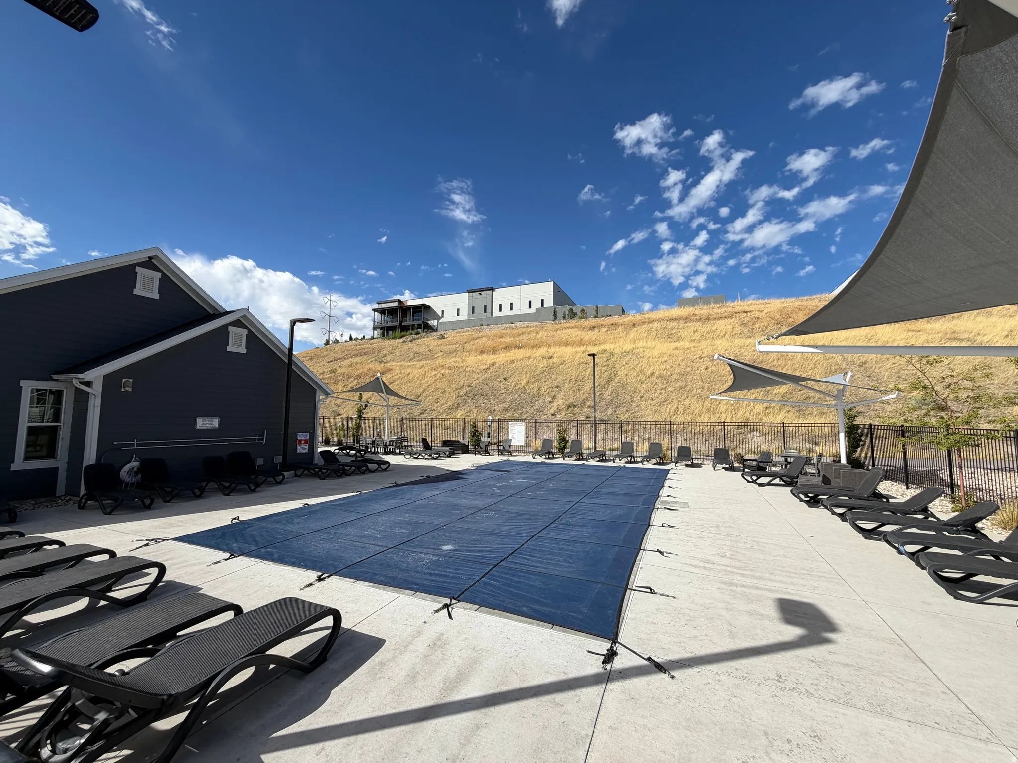 Outdoor pool area featuring a covered pool, concrete decking, and multiple shade structures