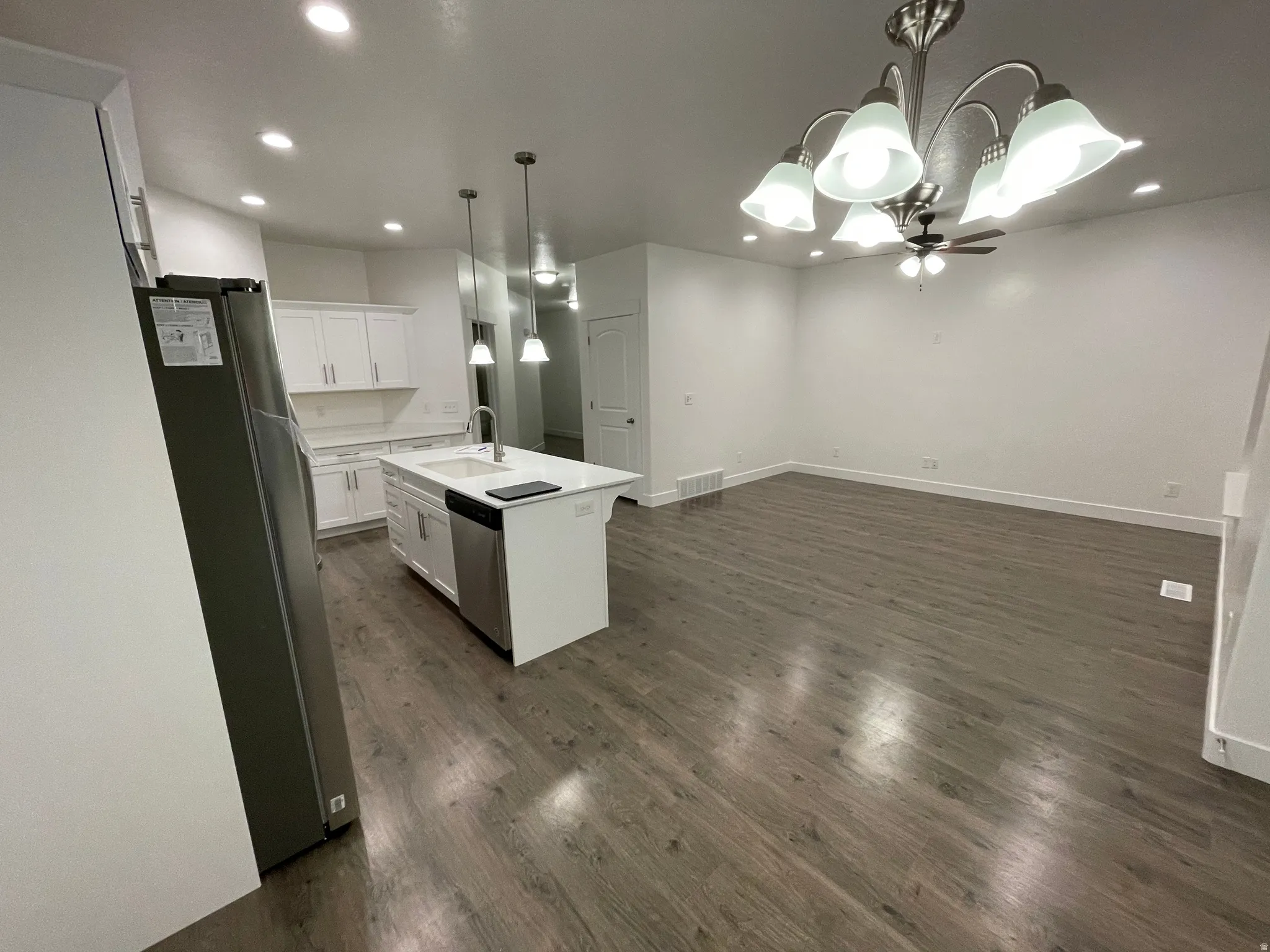 Open-concept living area with wood-finish flooring, recessed lighting, and a chandelier with a ceiling fan
