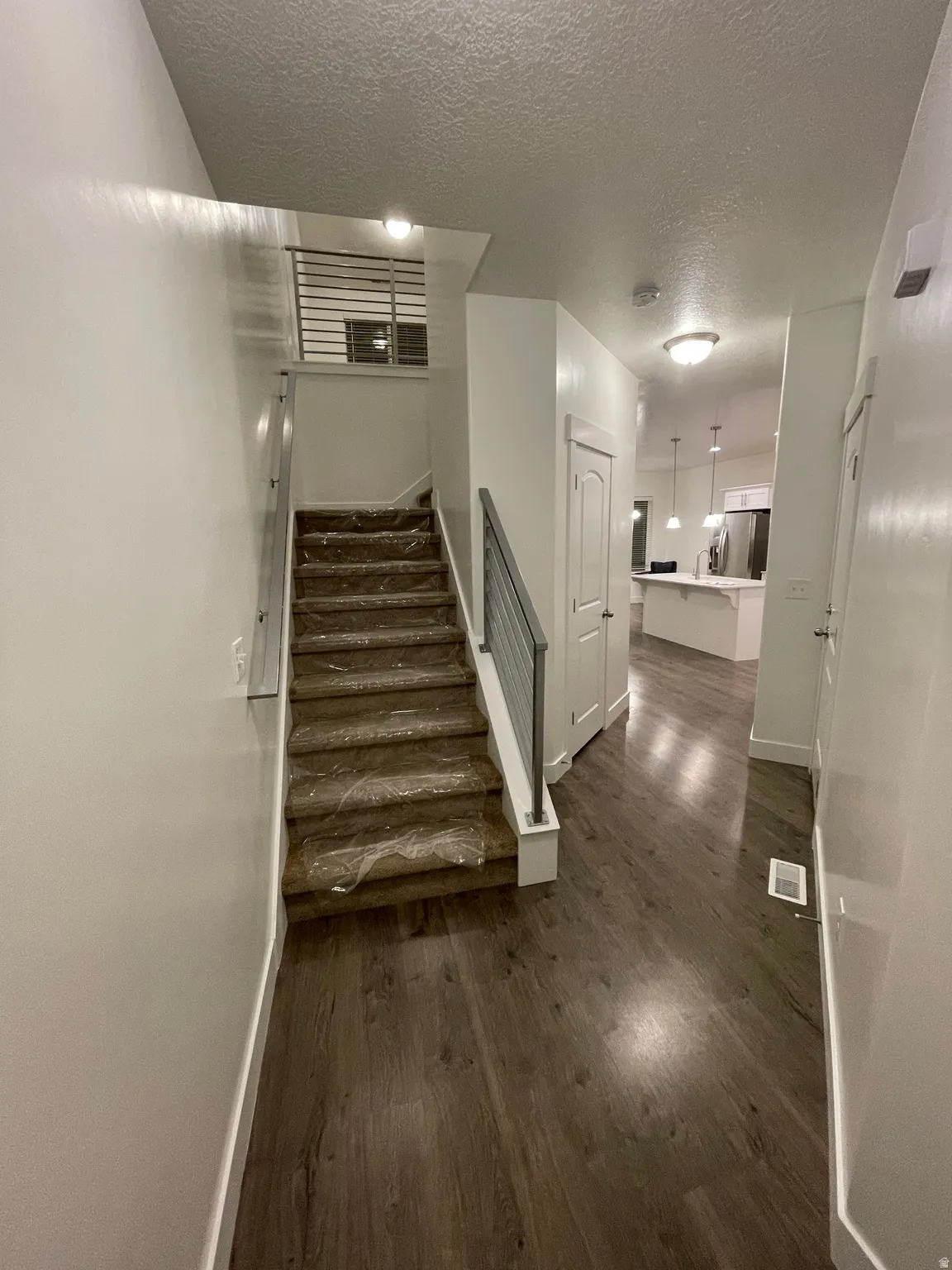 Modern staircase with metal railings, wood-finish flooring, and recessed lighting