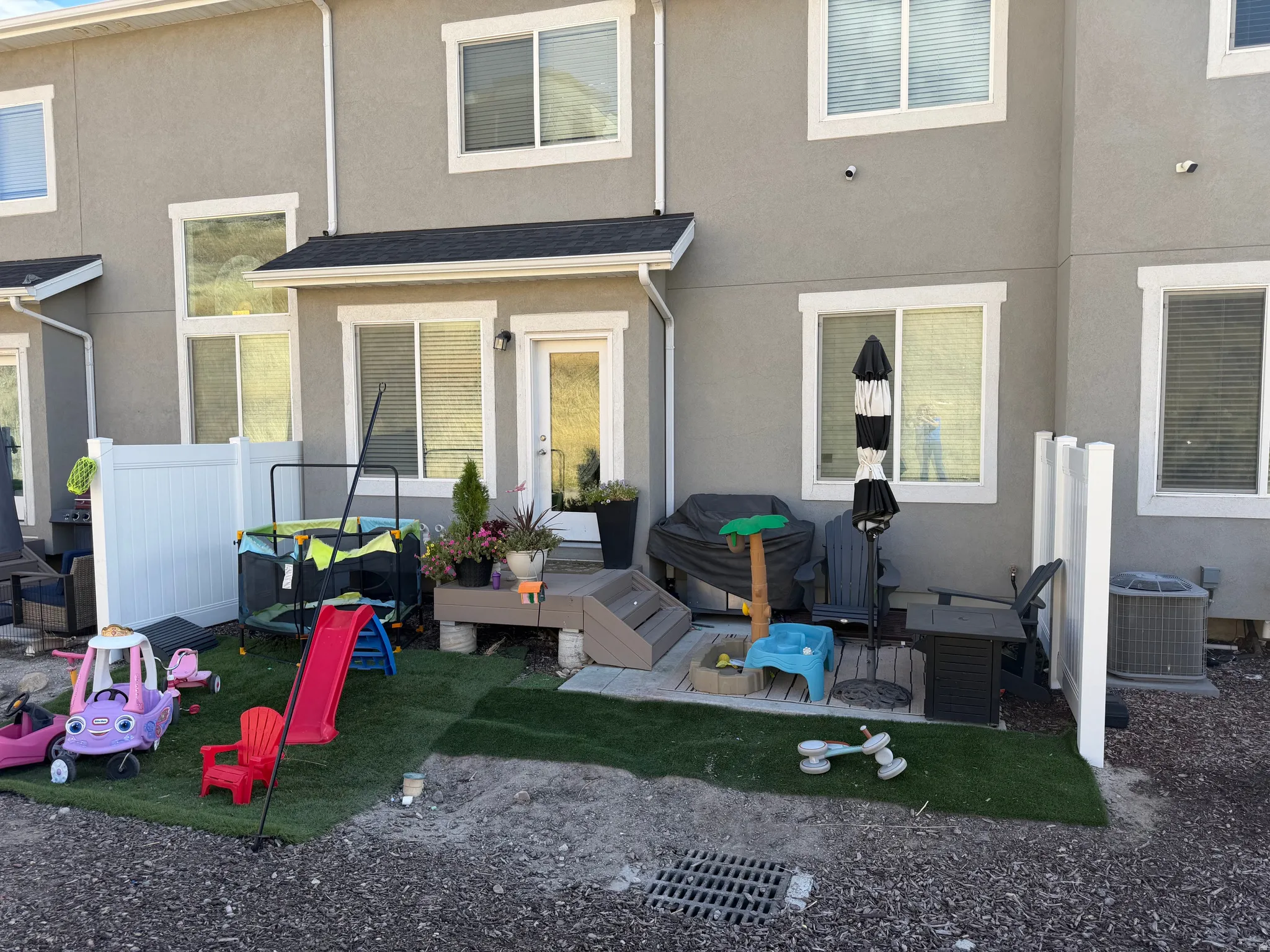 Private patio space with a wooden deck, artificial turf, and white vinyl fencing