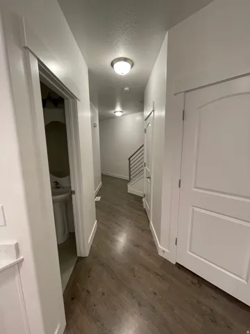 Hallway featuring wood-finish flooring, recessed lighting, and a modern staircase with metal railings