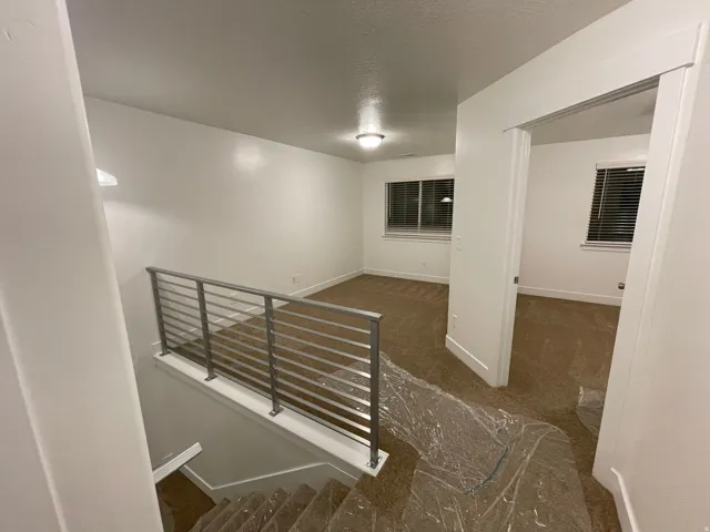 Upper-level space featuring neutral carpeting, white trim, recessed lighting, and a modern metal railing