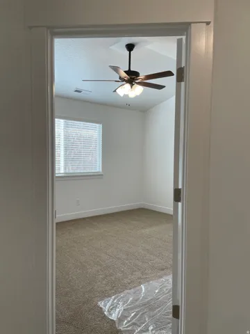 Room featuring neutral carpeting, a ceiling fan with integrated lighting, window with blinds, and white trim